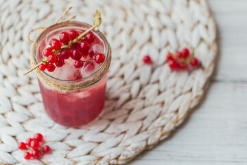 Glass jar of red currant soda drink on white wooden table. Summer healthy detox lemonade, cocktail or another drink background. Low alcohol, nonalcoholic drinks, super food or healthy diet concept.