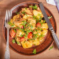 Italian cuisine - Arrabbiata garlic chicken with potatoes in a clay plate on the table, close-up, top view, rustic style