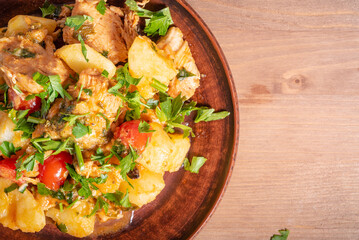 Italian cuisine - Arrabbiata garlic chicken with potatoes in a clay plate on the table, close-up,...