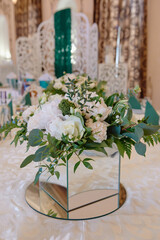 Beautiful floral arrangement of rose flowers and greenery on wedding table in restaurant, copy space. Luxury wedding decorations. Table setting