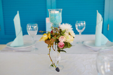 Beautiful floral arrangement of rose flowers and greenery in vase on wedding table in restaurant,...