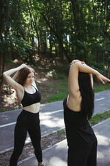 Friendship, personal trainer, group workout. Young fit women stretching hands during outdoor training. Active and healthy lifestyle