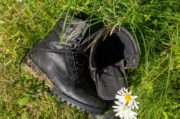 Old leather Hiking boots in the green grass. Summer is a time of travel. Close up.