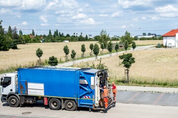 The garbage truck is going to collect garbage along the city street. Poland.