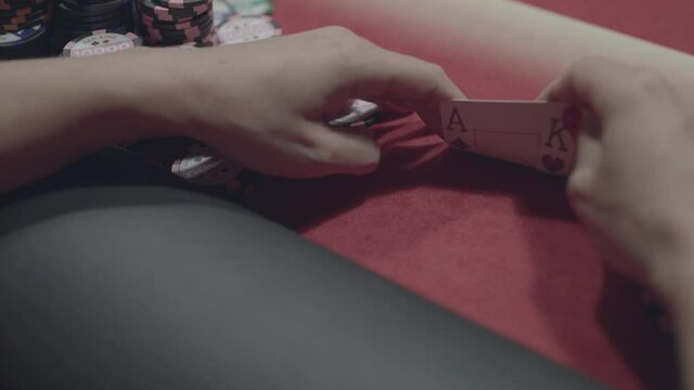 Female hands raise cards tidily to spy while playing in the casino