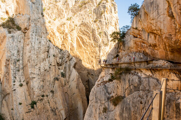 El Caminito del Rey walkway along the steep walls of a narrow gorge in El Chorro, narrow wooden platforms attached to vertical rocks over the precipice, renewed tourist attraction.