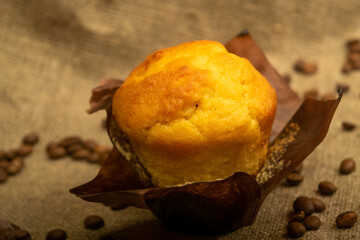 Fresh cupcake, coffee beans and chocolate on a homespun fabric with a rough texture. Close up.