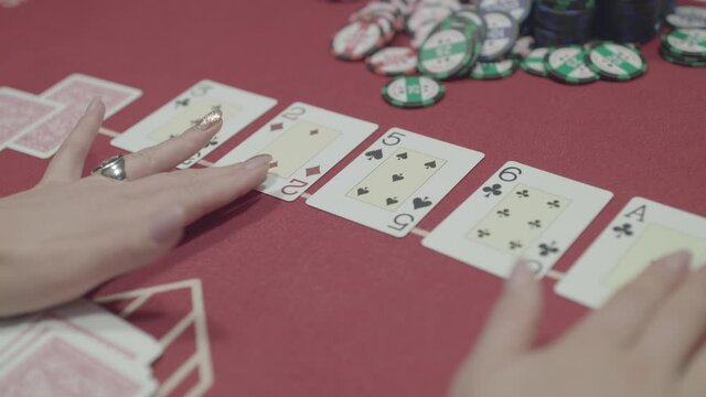 Female hands touch the cards laid out on the table while playing poker