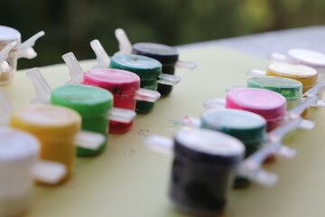 multicolored watercolor paint bottles with different colors like white, black, yellow, green, pink