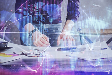 Double exposure of Man writing in notepad with business icons on background.