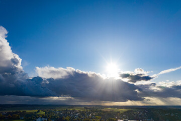 Sonnenstrahlen leuchten über und unter einer Wolke heraus und erhellen die Landschaft