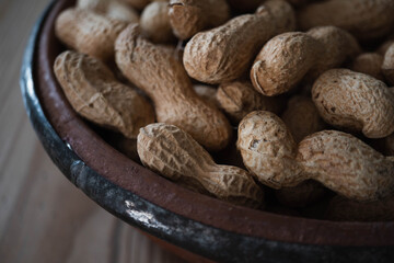 Macro shot of a bowl of raw peanuts or monkey nuts.  Moody atmosphere and crisp focus on texture of the peanut shell