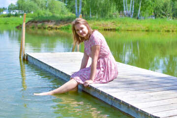 beautiful resting woman sitting on a wooden pier in nature