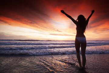 Woman in bikini by sea at sunset
