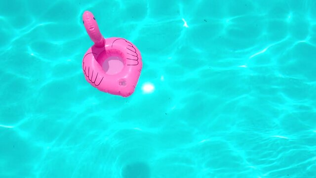 Flamingo Shaped Inflatable Ring Floating On Swimming Pool During Sunny Day.
