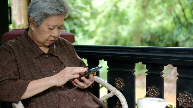 asian elder senior woman using mobile smart phone. elderly female holding cellphone. mature retirement lifestyle
