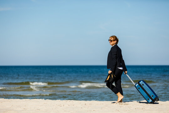 Woman with suitcase walking on beach
