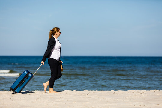 Woman with suitcase walking on beach
