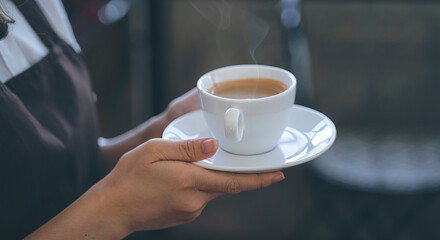 young barista serving hot coffee for her customer.