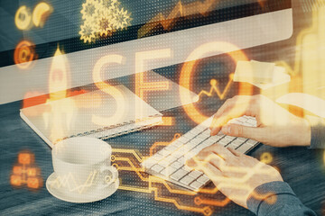 Multi exposure of seo icon with man working on computer on background. Concept of search engine optimization.