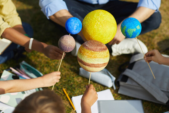 Close Up Of Group Of Children Holding Model Planets While Enjoying Outdoor Astronomy Class In Sunlight, Copy Space