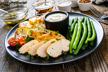 Roast chicken fillets with green beans and fried potatoes  on wooden table
