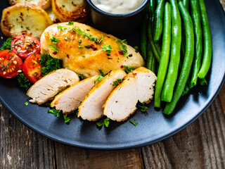 Roast chicken fillets with green beans and fried potatoes  on wooden table
