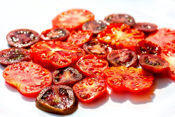 Top view of slices of differet colors and forms of ripe tomatoes. Food abstract background. Red and black tomatoes on white background.