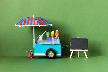 Ice cream toy cart with blue red umbrella. Assortment of ice cream empty menu black chalkboard....