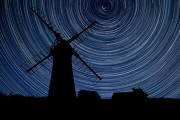 Digital composite image of star trails around Polaris with Windmill in stunning landscape - Powered by Adobe