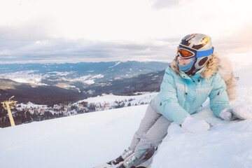 Fototapeta na wymiar Adult caucasian woman skier rides a ski resort on a background of mountains and ski resort in down 