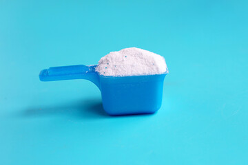 Detergent powder with measuring spoon for clothes washing. Laundry concept.