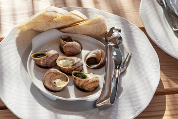 A plate with cooked snails and cutlery for eating snails.