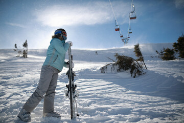 Fototapeta na wymiar A woman posing with ski in mountain ski resort in winter season,sunny day