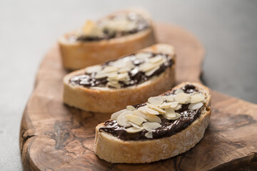 Rustic ciabatta with organic chocolate cream and almond flakes on olive wood board