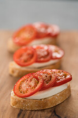 Simple bruschetta with tomatoes and mozzarella on olive wood board
