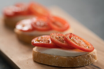 Simple bruschetta with tomatoes and mozzarella on olive wood board