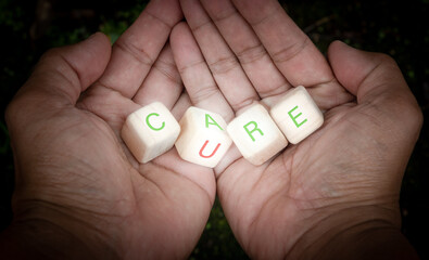 Care and cure Word concept with wood dice and hands