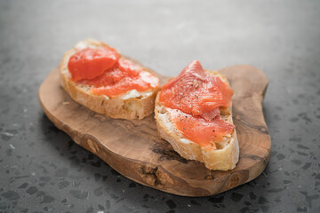 Sandwich with smoked salmon and cream cheese on olive woob board