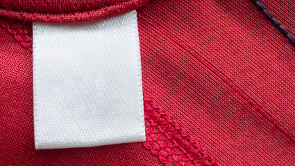 White blank laundry care clothes label on red polyester sport shirt background