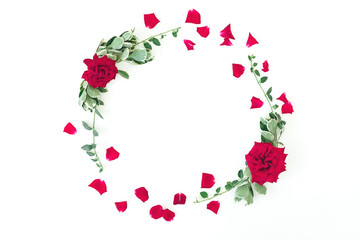 Round frame made of red roses flowers and green leaves on white background. Flat lay