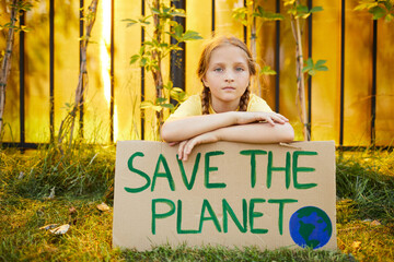 Portrait of cute teenage girl holding sign with SAVE THE PLANET and looking at camera while protesting for nature outdoors, copy space