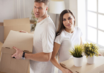 Cute couple unpacking cardboard boxes in their new home