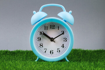 Alarm clock on grass or lawn background - time concept.