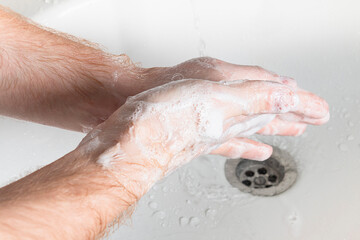 Fototapeta premium Man use soap and washing hands under the water tap. Hygiene concept hand detail.