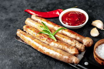 
Grilled meat sausages over a meat knife on a stone background
