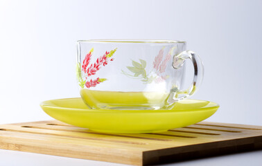 Glass cup with a floral pattern on a green saucer.
