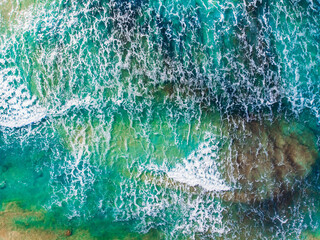 Small turquoise waves for surfing on shallows of sea low tide or ebb, aerial top view