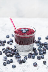 Healthy breakfast or morning snack with chia seeds and blueberries on white stone background, vegetarian food, diet and health concept.