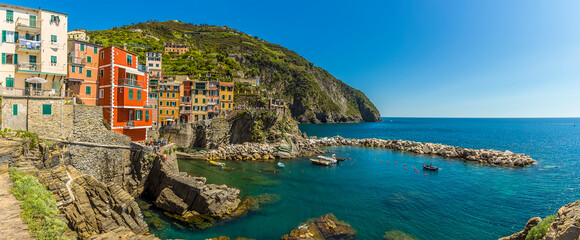 Fototapeta na wymiar A panorama view of colourful houses and crystal clear waters in the Cinque Terre village of Riomaggiore, Italy in the summertime